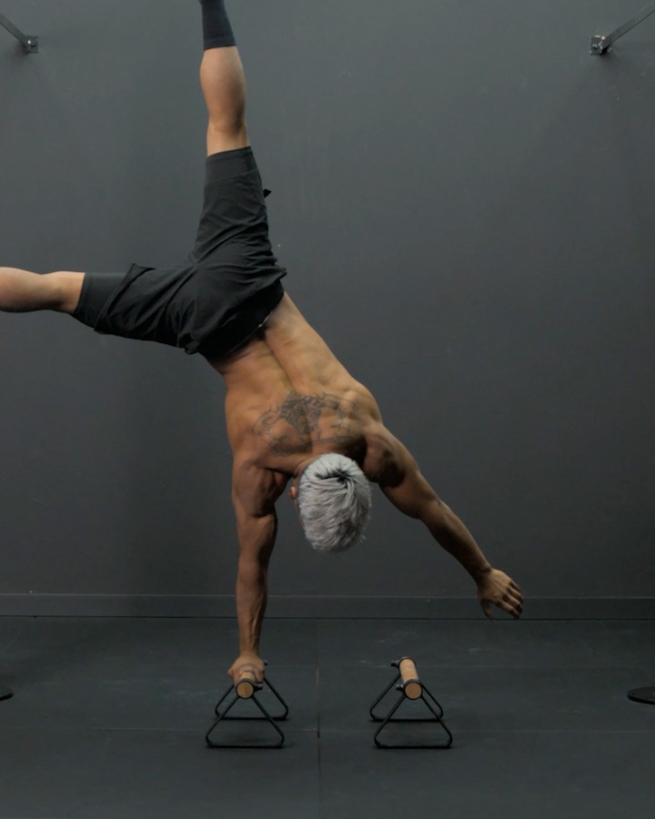 Straddle-Handstand-Flagge auf einem Arm